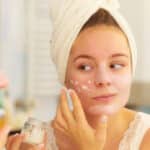 woman applying mask cream on face in bathroom