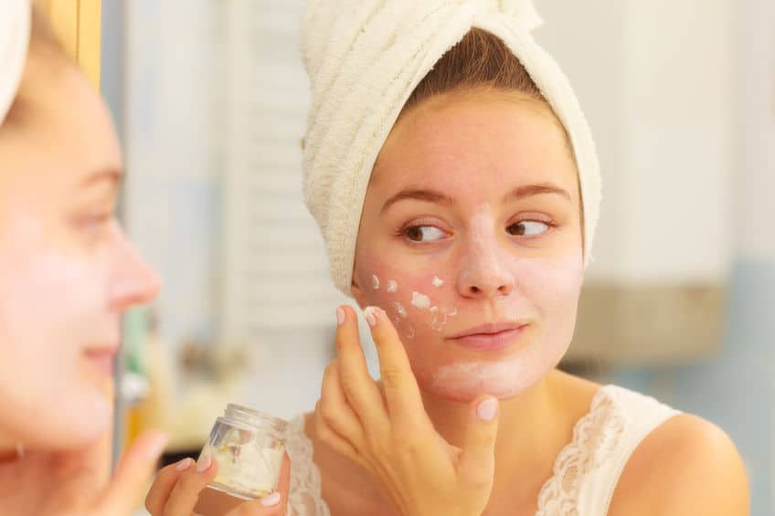 woman applying mask cream on face in bathroom